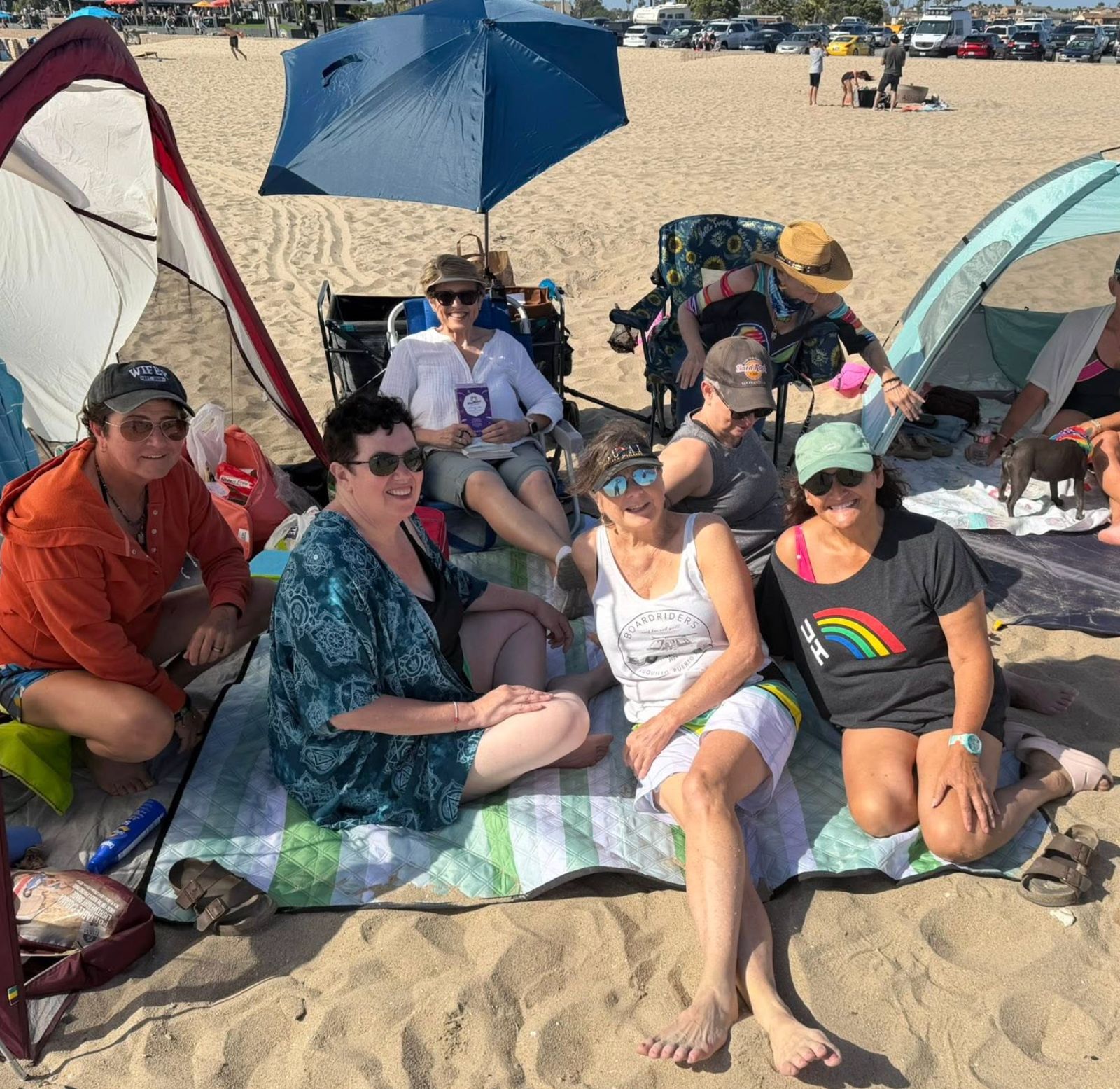 A group of friends gathered at the beach under umbrellas